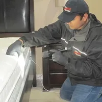 Bed bug inspection technician checking a mattress and bed frame for signs of infestation in Columbia, SC