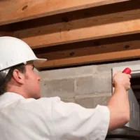 Termite inspection technician checking a basement wall and framing for termite activity in Columbia, SC